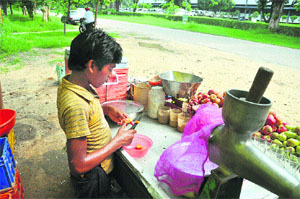 A child prepares fruit juice while standing near the PAU in Ludhiana on Friday.