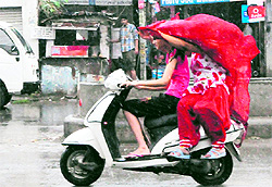 A mother-daughter duo rides a scooter during rain in Amritsar on Sunday