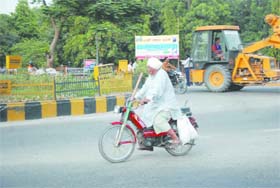 An elderly person rides a moped as he makes his way near the Rose Garden roundabout in Bathinda on a sunny Sunday