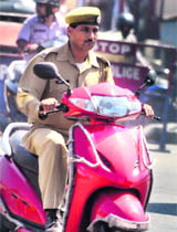 A policeman without wearing helmet rides a scooty in Jammu. The vehicle does not carry a registration plate. 
