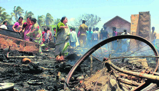 People look at their charred articles after a fire broke out in a slum in Chennai on Sunday.