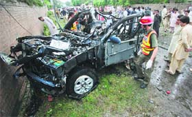 A rescue worker surveys a damaged vehicle after it was hit by a bomb in Peshawar