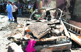 Syrians inspect the site of a car bomb that ripped through Jaramana, a mainly Christian and Druze suburb of Damascus, on Monday