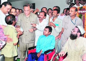 Chief Minister Vijay Bahuguna gives cheques to physically challenged persons at a camp organised for them in Dehradun on Tuesday