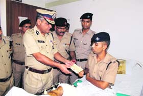 DGP Vijay Raghav Pant gives a cheque to Ramesh Chand Painuli, a fireman, in Dehradun on Tuesday