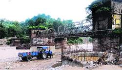Over one-century old Kotla Bridge on Dehar Khud on the Pathankot-Mandi national highway along with the new bridge whose construction has been going on at a snails pace. Photo: Rajiv Mahajan