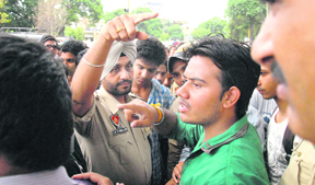 A police official tries to control the protesters in Jalandhar on Tuesday.