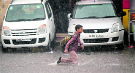 A boy wades through a waterlogged road.