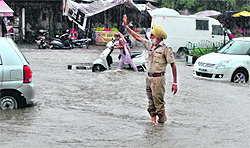 A policeman navigates traffic on a waterlogged road in Patiala on Tuesday