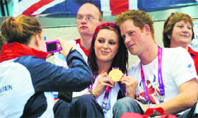 Prince Harry poses for photographs with Great Britain swimming gold medalist Jessica-Jane Applegate during a visit to the Aquatics Centre in London.