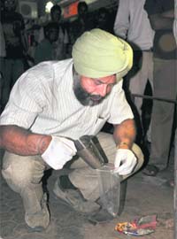A member of the forensic team of the Chandigarh police examines the crime spot in Sector 22, Chandigarh, on Saturday
