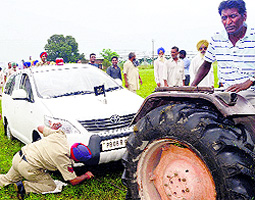 Policemen try to take out Deputy Commissioner Priyank Bhartis car which was stuck in a muddy area near Kartarpur in Jalandhar on Saturday