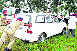 Policemen try to take out Deputy Commissioner Priyank Bhartis car which was stuck in a muddy area near Kartarpur in Jalandhar on Saturday