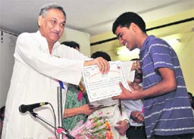 Chief Minister Vijay Bahuguna honours a student at a function in Dehradun on Sunday