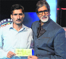 Manoj Kumar Raina receives a cheque for ~1 crore from Kaun Banega Crorepati host Amitabh Bachchan.