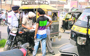 Policemen issue challans to auto-rickshaw drivers during a drive in Ludhiana.