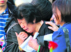 A woman cries as she leans on a friend near the name of Thomas Tong, who died in the attacks, at the South Pool wall of the 9/11 Memorial during a service.