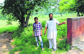A priest of the cremation ground shows the incomplete boundary wall of the burial ground at Sector 25 in Chandigarh. 