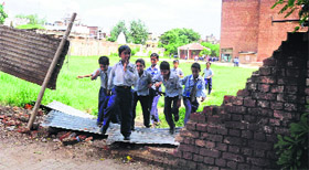 Schoolchildren pass through the broken boundary wall of Government Senior Secondary School, Karsan, in Chandigarh. 