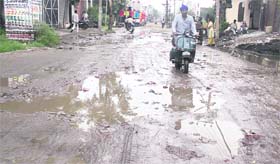 A man tries to wade through accumulated rainwater on the dilapidated Gujja Peer road in Jalandhar