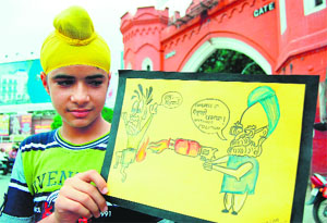 A boy shows a cartoon ridiculing the hike in LPG prices in Amritsar on Friday.
