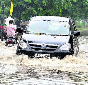 Vehicles wade through a waterlogged street in Sector 13 after a heavy rainfall in Karnal on Friday morning. 