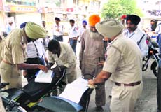Traffic policemen issue challans to drivers of overloaded auto-rickshaws at Ishmeet Chowk in Ludhiana on Friday.