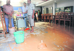 Workers drain out water from the library at the Dabur Dhanwantry Ayurvedic College and Hospital, Sector 46, in Chandiagrh on Monday.