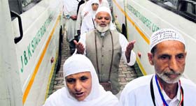 A Haj pilgrim prays as he walks between stationary buses along with other pilgrims during their departure for the annual pilgrimage to Mecca, in Srinagar on Monday.