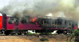 Smoke billows from a coach of a relief train set on fire after the accident in Bikaner district on Monday.