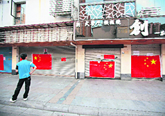 A man looks at large Chinese national flags covering the entrance to a Japanese restaurant in Suzhou.