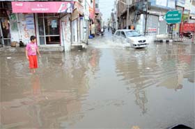 A boy watches as a car negotiates a waterlogged street in Bathinda after rains lashed the city on Tuesday afternoon