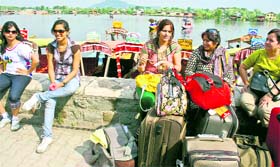 Tourists sit on parapet of the Boulevard Road near Dal Lake in Srinagar on Tuesday.