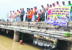 Members of a political outfit immerse an LPG cylinder into the Sidhwan Canal in Ludhiana on Tuesday.