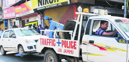 Traffic police crane carry a car which was parked in the no parking area of Jammu on Wednesday.