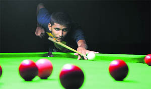 A cueist eyes the target during District Billiards and Snooker Cship in Jammu on Wednesday.