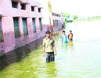 Students wade through knee-deep water in Government Senior Secondary School at Garnawathi village of Rohtak district on Friday. 