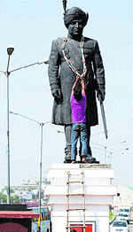 A worker decorates the statue of Maharaja Hari Singh, the last ruler of the state, ahead of his birth anniversary function in Jammu on Friday
