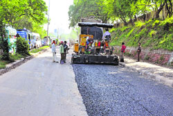 Workers of the Roads and Building Department repair a damaged road in Jammu on Friday.