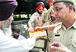 Policemen savour laddoos that were distributed after the Mayoral election in Ludhiana on Friday