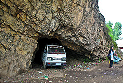 A girl waits for a bus next to a vehicle parked in a cave in Sander Koot Bola, Srinagar, on Saturday
