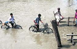 Villagers wade through flood water at Kanikuch in Kamrup district of Assam on Saturday. 