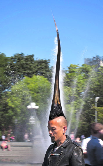 Japanese fashion designer Kazuhiro Watanabe, who holds the world record for the “Tallest Mohawk”, walks past a water fountain in Washington Square Park after a media event held by the Guinness World Records to launch their 2013 book edition in New York.