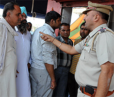 An accused being bundled into a police van; Civil Lines SHO Gurdev Bhalla speaks to the bystanders
