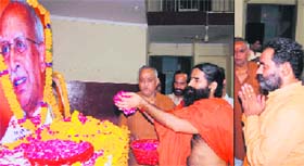 Yog guru Ramdev offers floral tributes to late RSS chief K Sudarshan at the Nishkam Sewa Bhawan in Haridwar; and (right) Haridwar Rural legislator Swami Yatishwaranand pays tributes