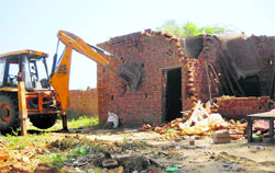 A JCB machine demolishes an unauthorised structure on the Jind road in Gohana on Thursday. Photo: BS Malik