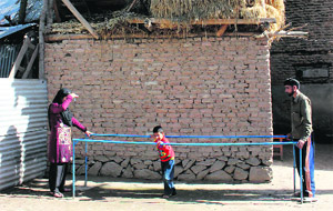 Mohammad Yasin, accompanied by his father and a woman HDC staff member, on a walking frame at their Safapora residence. 