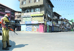 A CRPF jawan stands next to the shuttered shops in Srinagar on Thursday. 