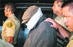 Nakoula Basseley Nakoula (C) is escorted out of his home by the police in Cerritos, California