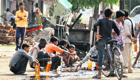 Migrants collect oil that fell on a road after an electricity transformer was hit by a heavy vehicle on the Metro Road in Ludhiana.